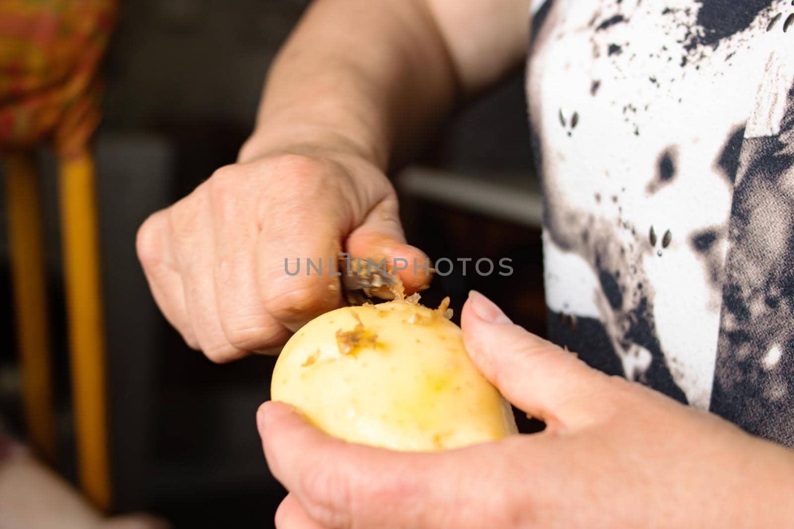 Hands peeling potatoes with a knife close up