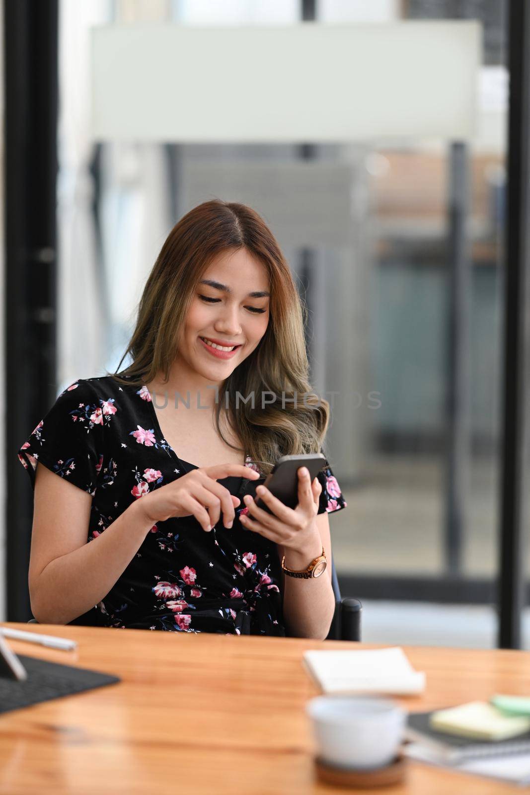 Beautiful young asian woman sitting in cafe and using smart phone.