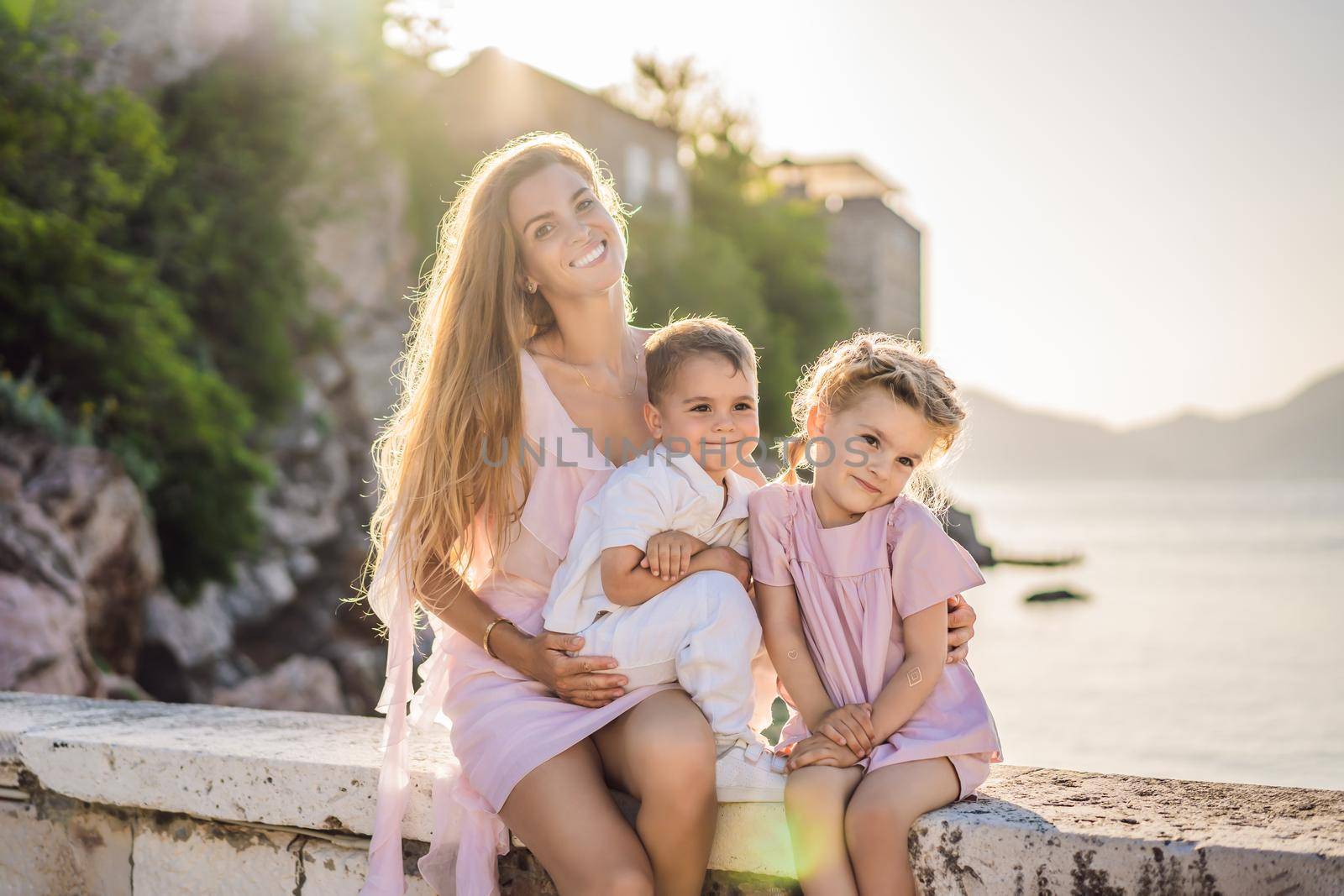 Mother and two children daughter and son tourists on background of beautiful view St. Stephen island, Sveti Stefan on the Budva Riviera, Budva, Montenegro. Travel to Montenegro concept.