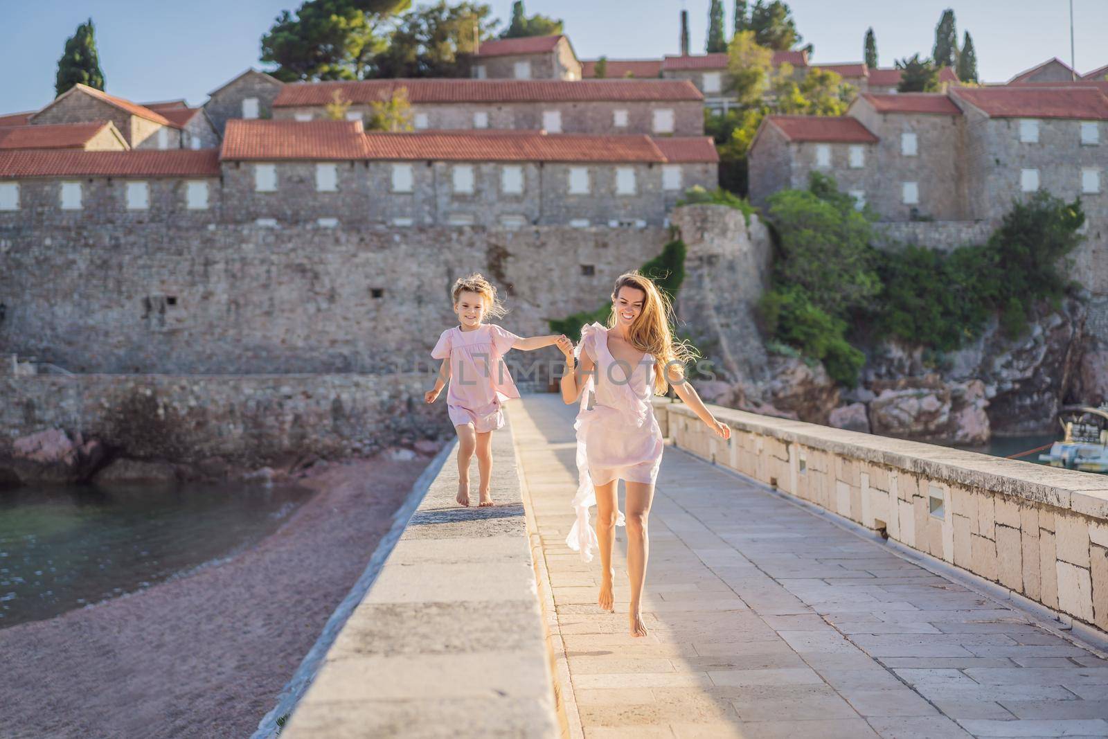 Mother and daughter tourists on background of beautiful view St. Stephen island, Sveti Stefan on the Budva Riviera, Budva, Montenegro. Travel to Montenegro concept.