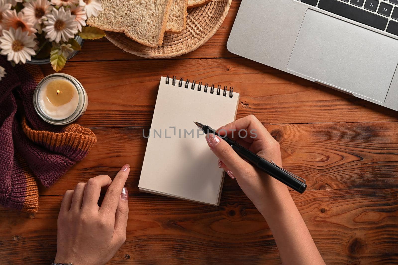 Creative woman holding pen and writing on empty notebook.