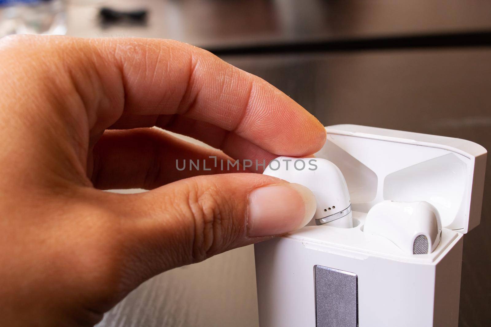 Hand takes out white wireless earbuds close up