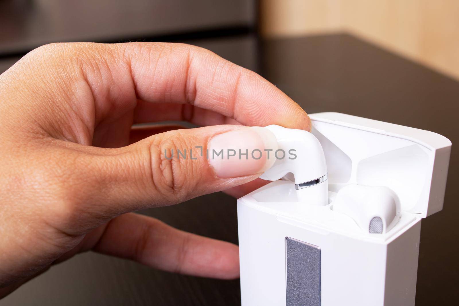 Hand takes out white wireless earbuds close up