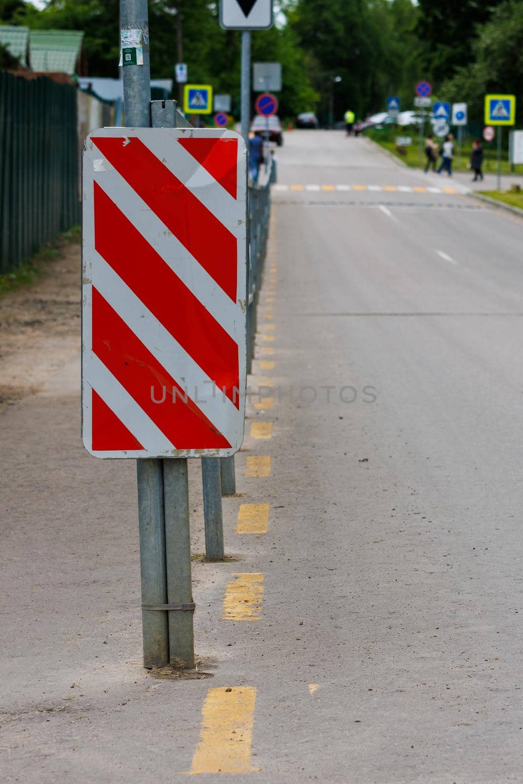 warning red and white diagonal striped vertical marking 8.22.2 sign at the end of road fence, separating road and