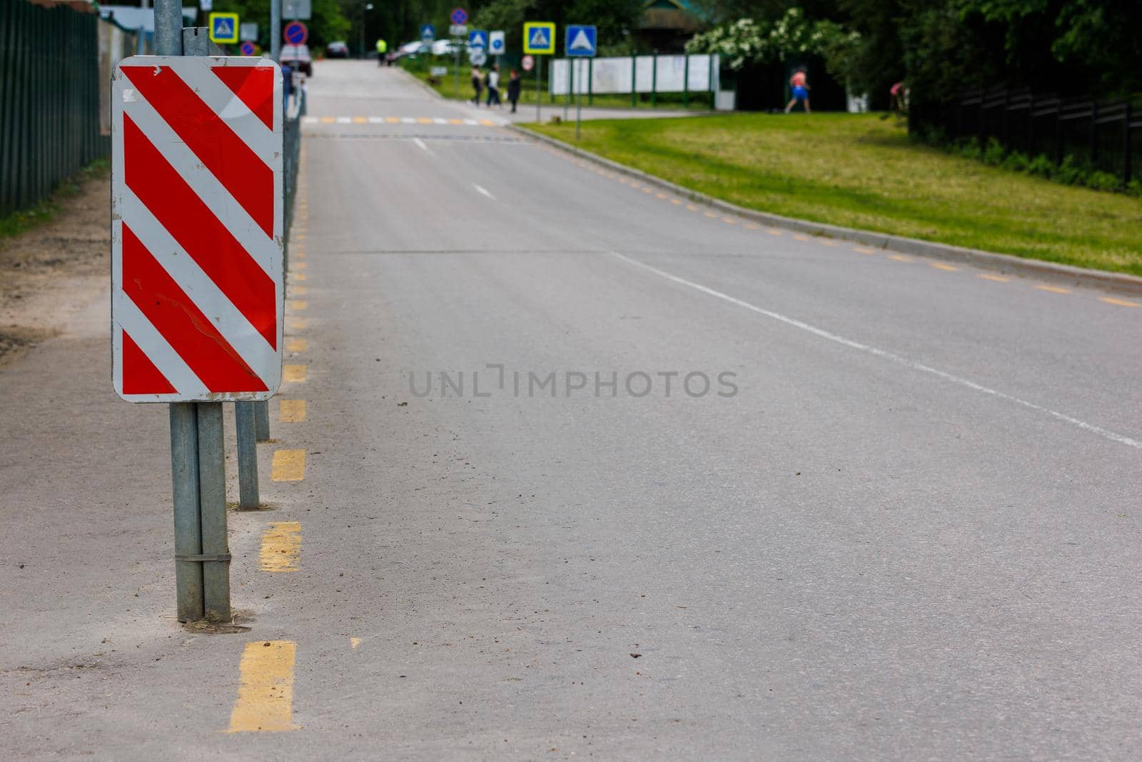 warning red and white diagonal striped vertical marking 8.22.2 sign at the end of road fence, separating road and