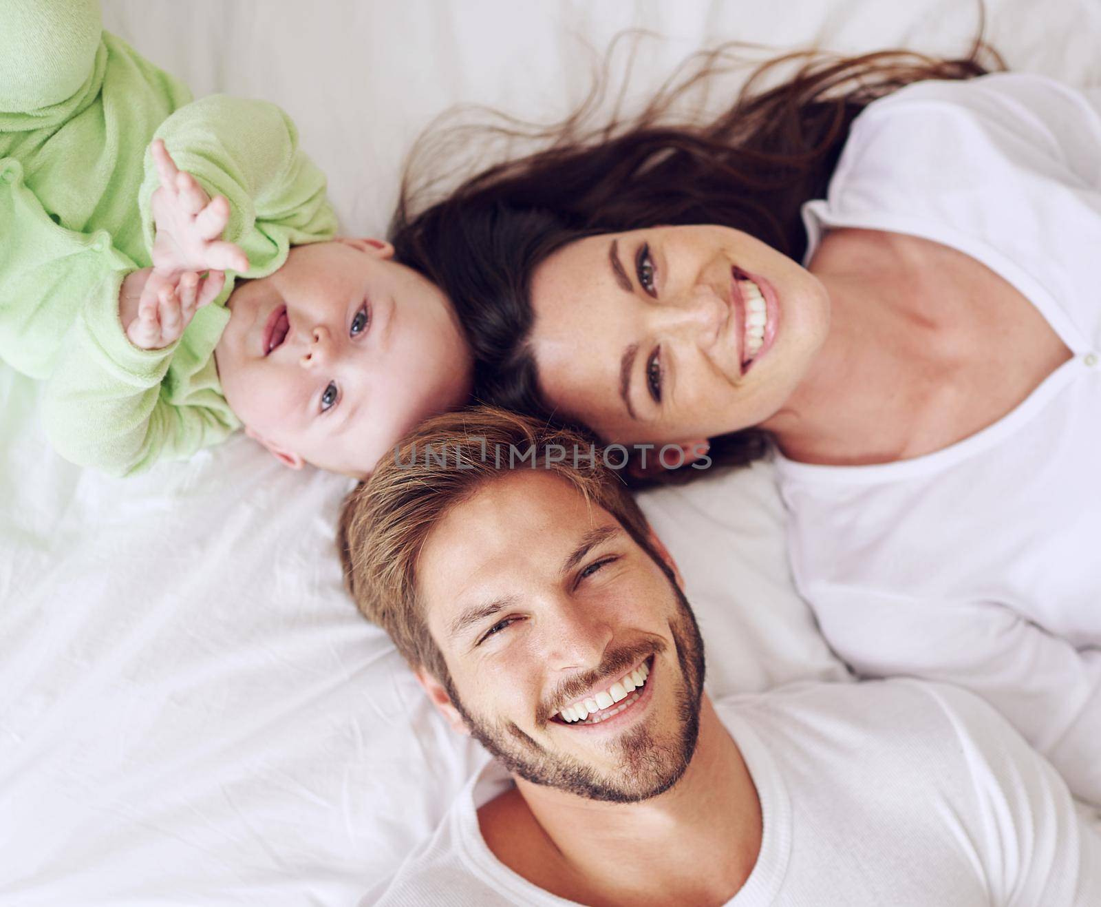 High angle portrait of a young couple and their baby boy in the bedroom.