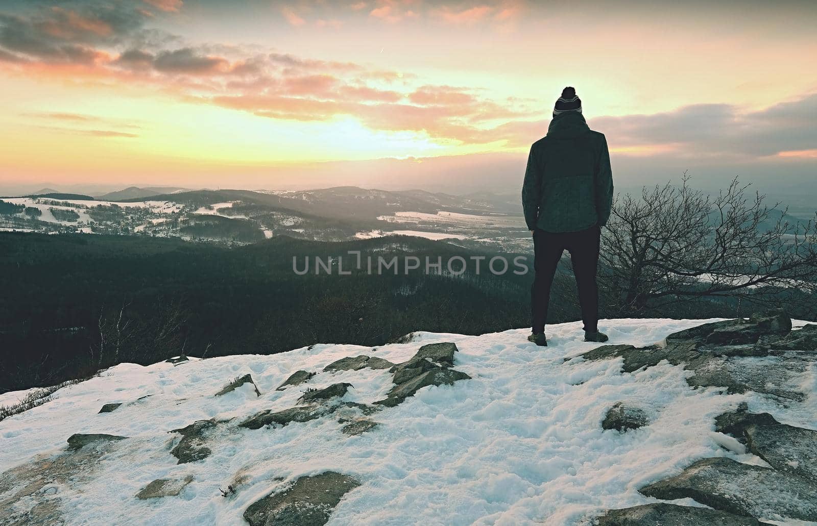 Man on rocks and looking at the snow-covered hills. Dark sky  by rdonar2