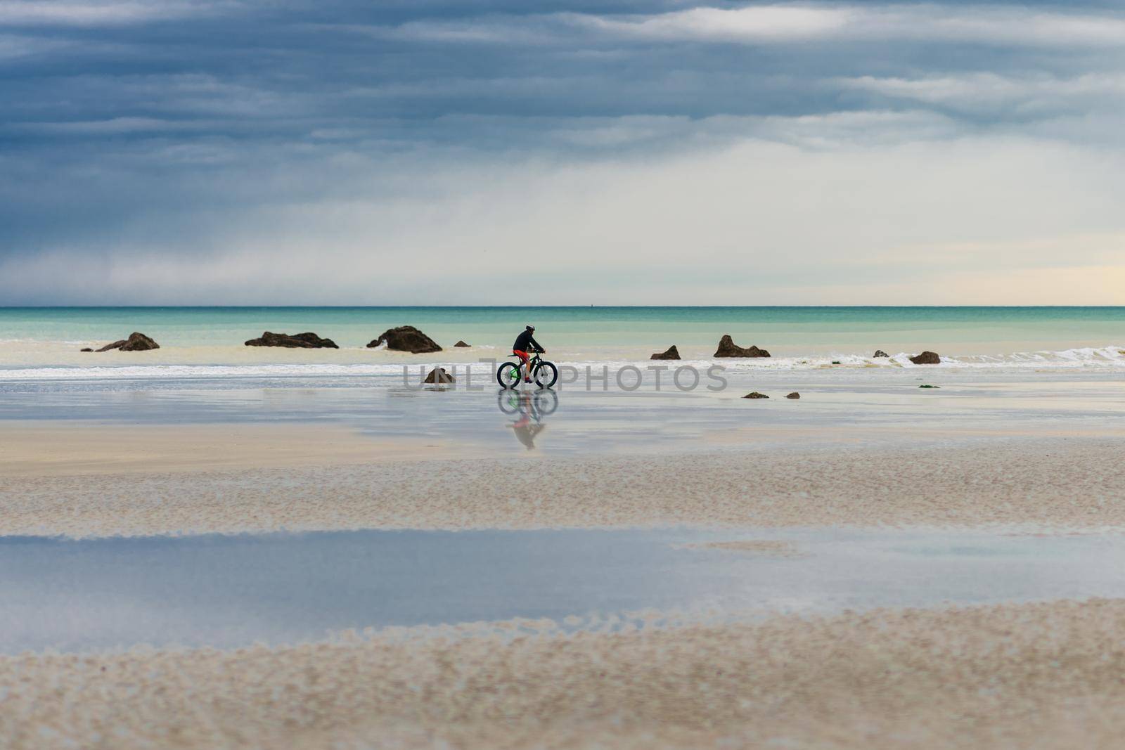 Cyclist rides a bike along the Atlantic Ocean at Normandy