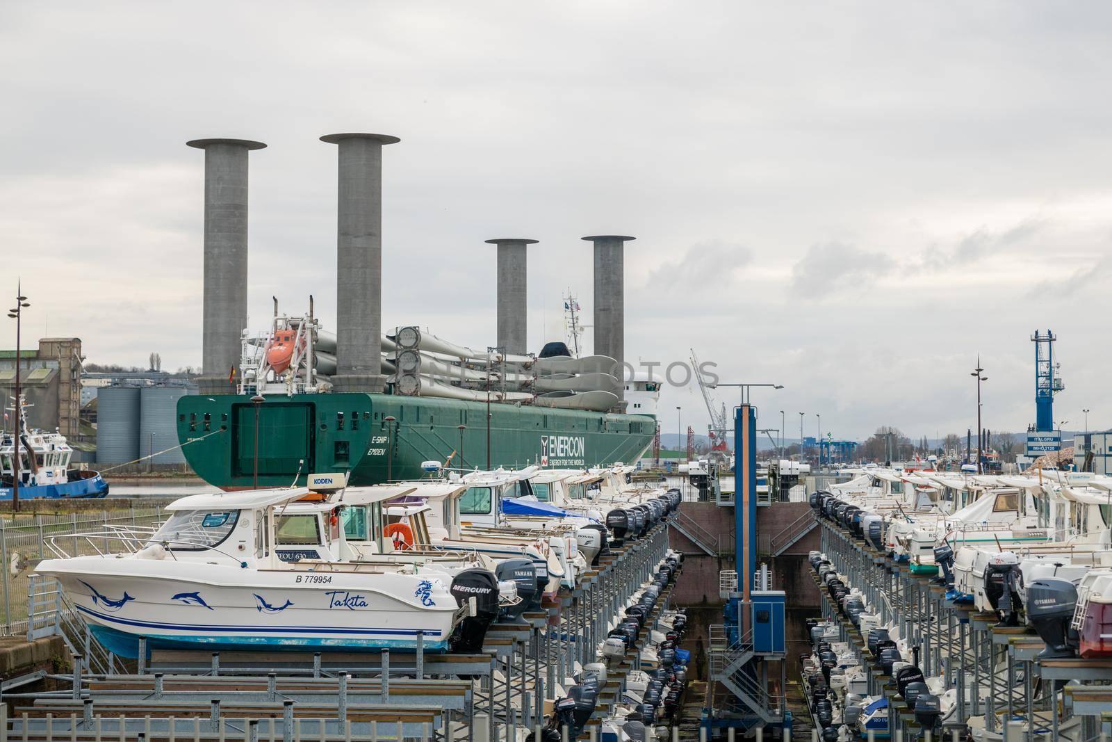 DIEPPE, FRANCE - DECEMBER 24, 2018: Maritime transport of wind turbine blades and motor boat parking at a port of Dieppe in Normandy