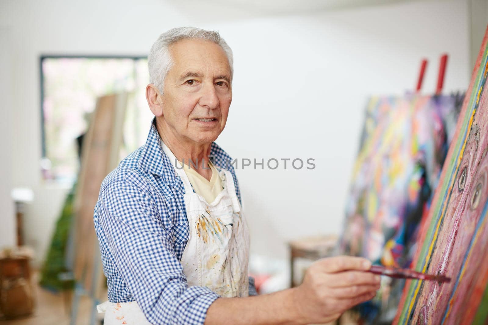 Life isnt about finding yourself, its about creating yourself. Shot of a senior man working on a painting at home. by YuriArcurs