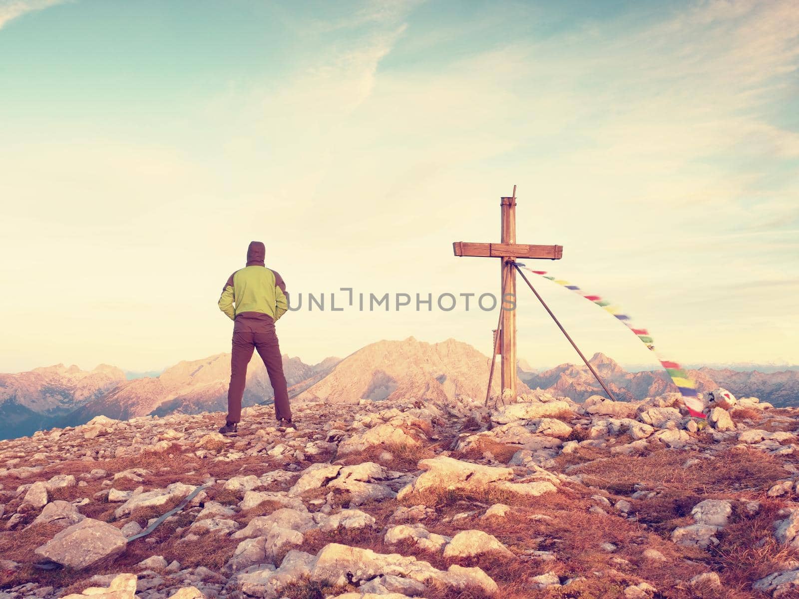 Alone man climber near the summit cross on peak, Dolomite Alps, Austria. Sunny windy evening, great visibility