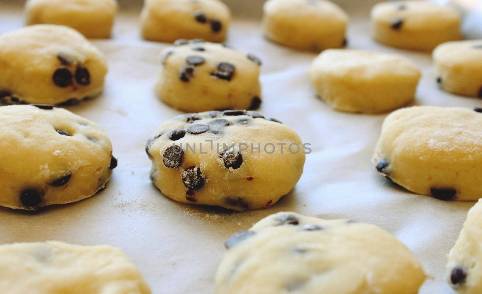 Close up of home made chocolate chip cookies / biscuits on baking paper ready for the oven