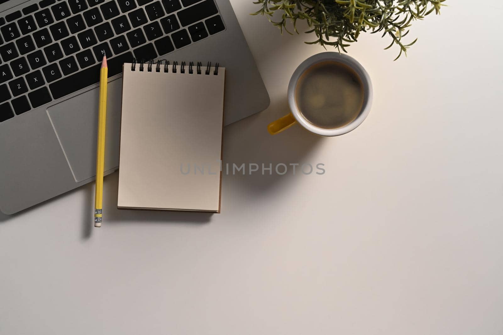Empty notepad, pencil, laptop computer and coffee cup on white table. by prathanchorruangsak