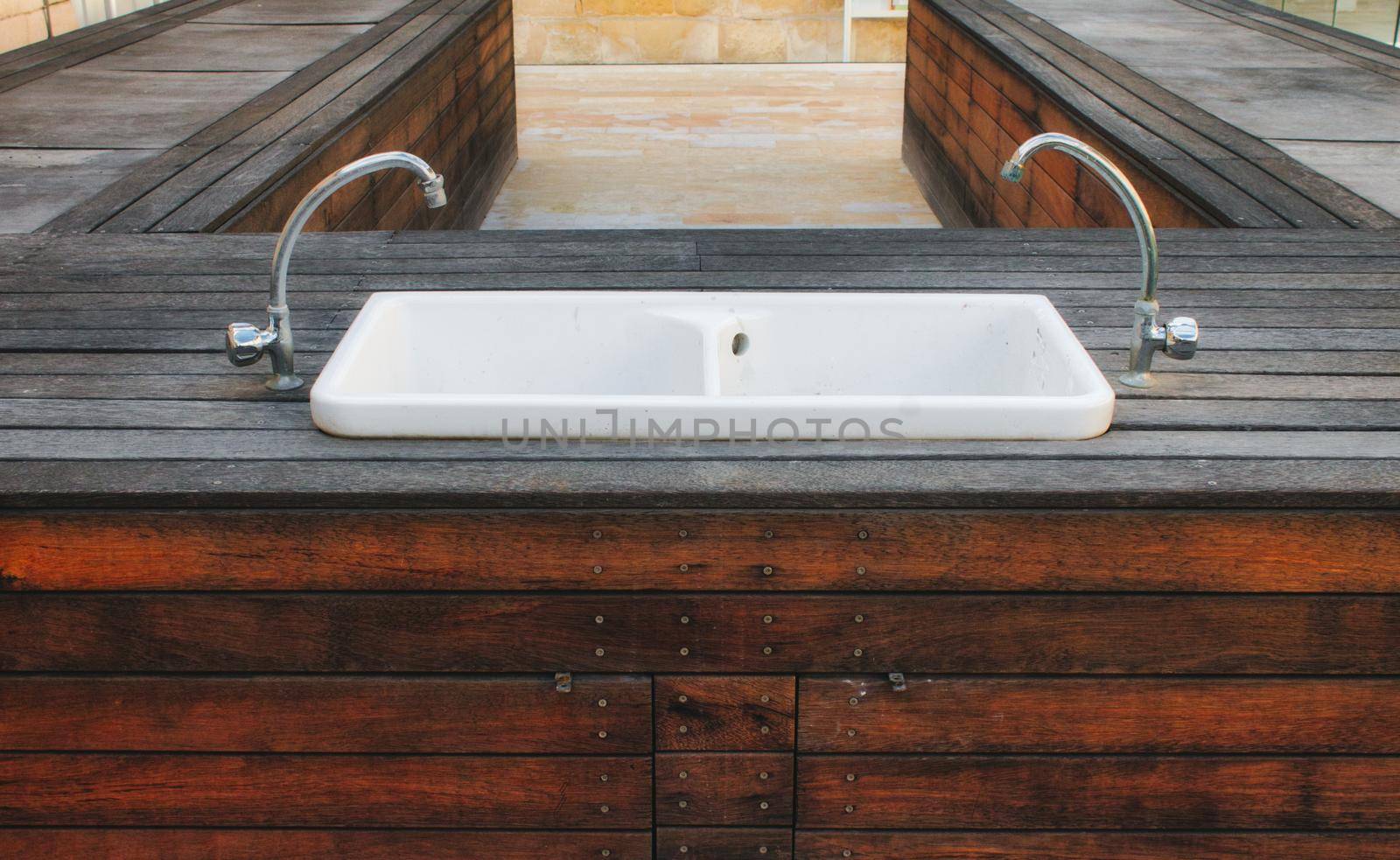 Porcelain hand wash basin set in a wooden platform outside in a modern stylish garden