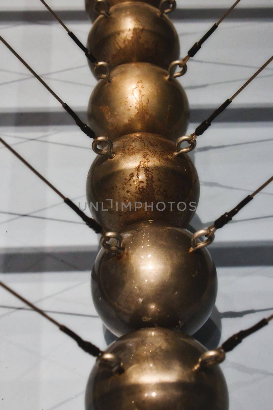 Close-up of a Newton's cradle made up of a row of large copper balls by tennesseewitney