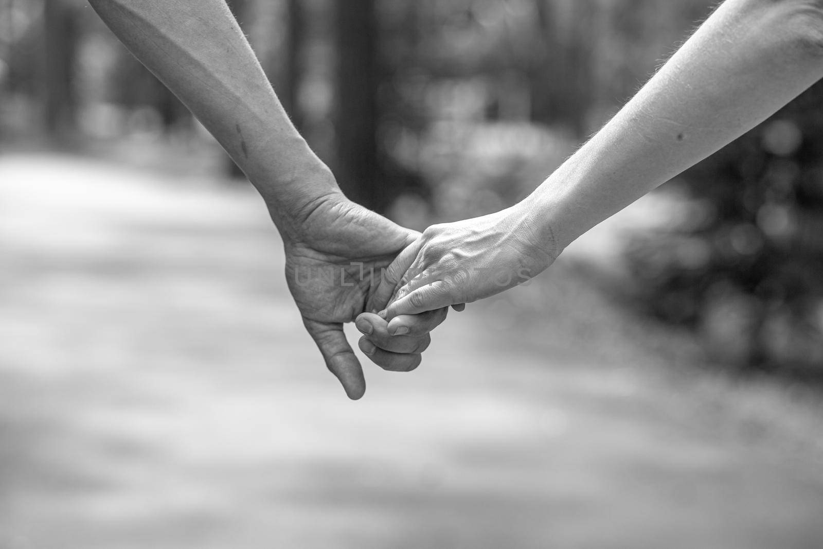 The husband's hand firmly holds the wife's hand close-up. Loving couple walking and holding hands. Reliable and strong marriage. The concept of romance, fidelity in marriage and love. Black and white