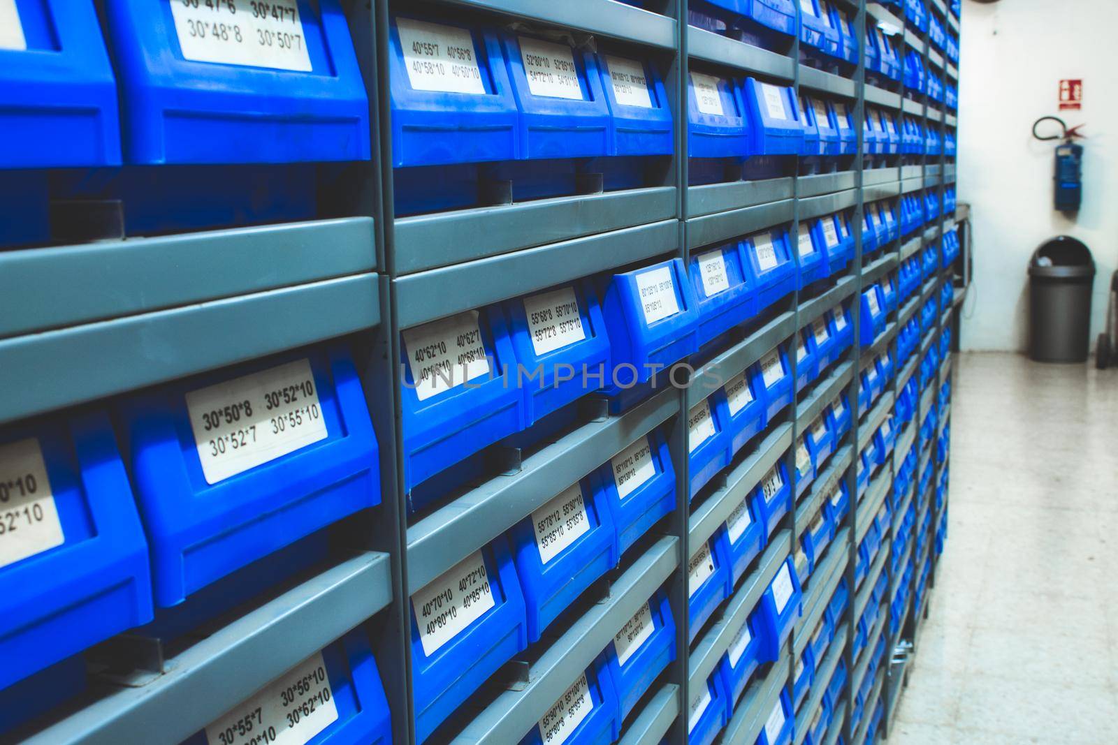 Blue plastic draws of stock / parts in rows of shelves in a warehouse
