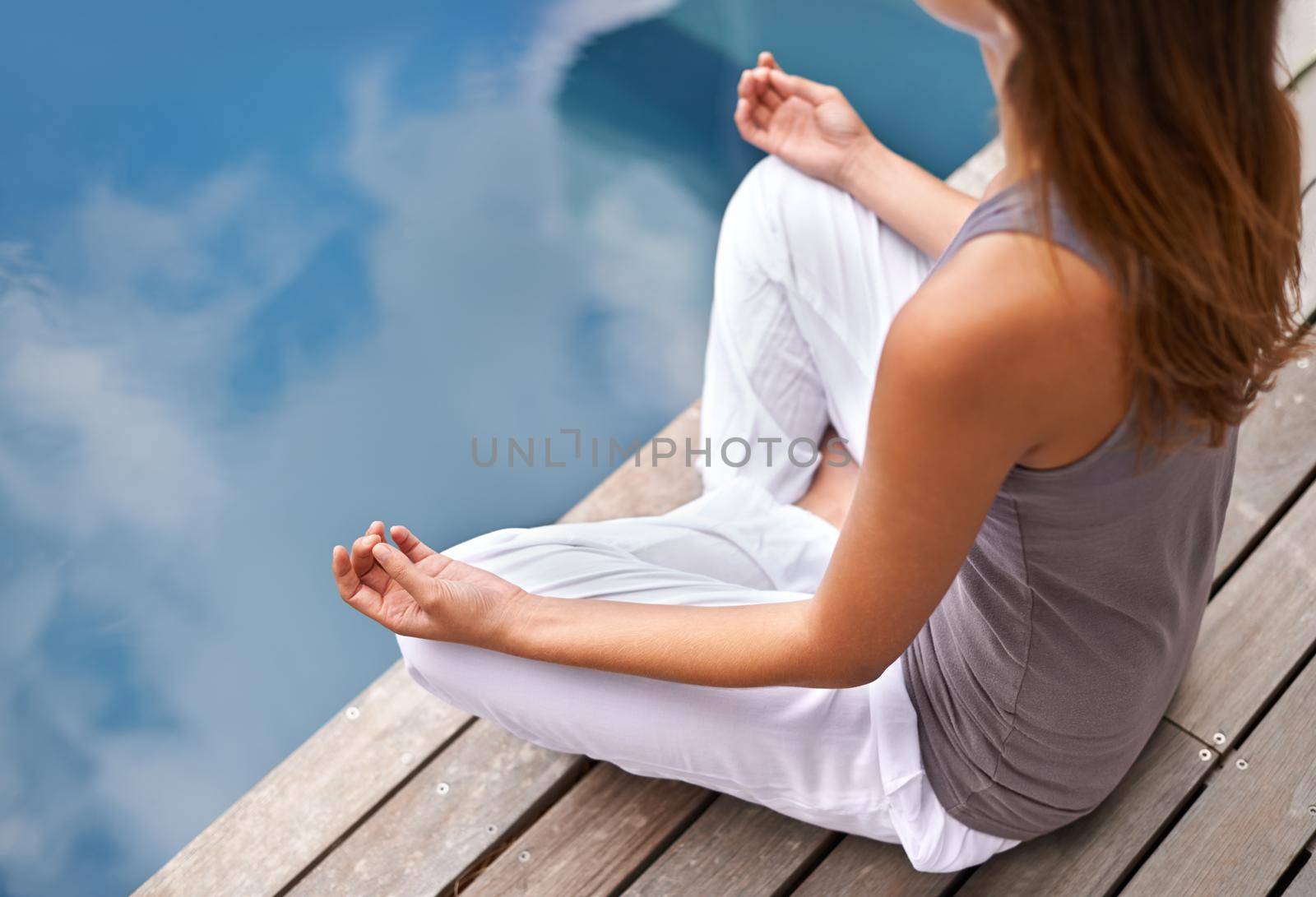 Cropped closeup of a young woman meditating poolside.