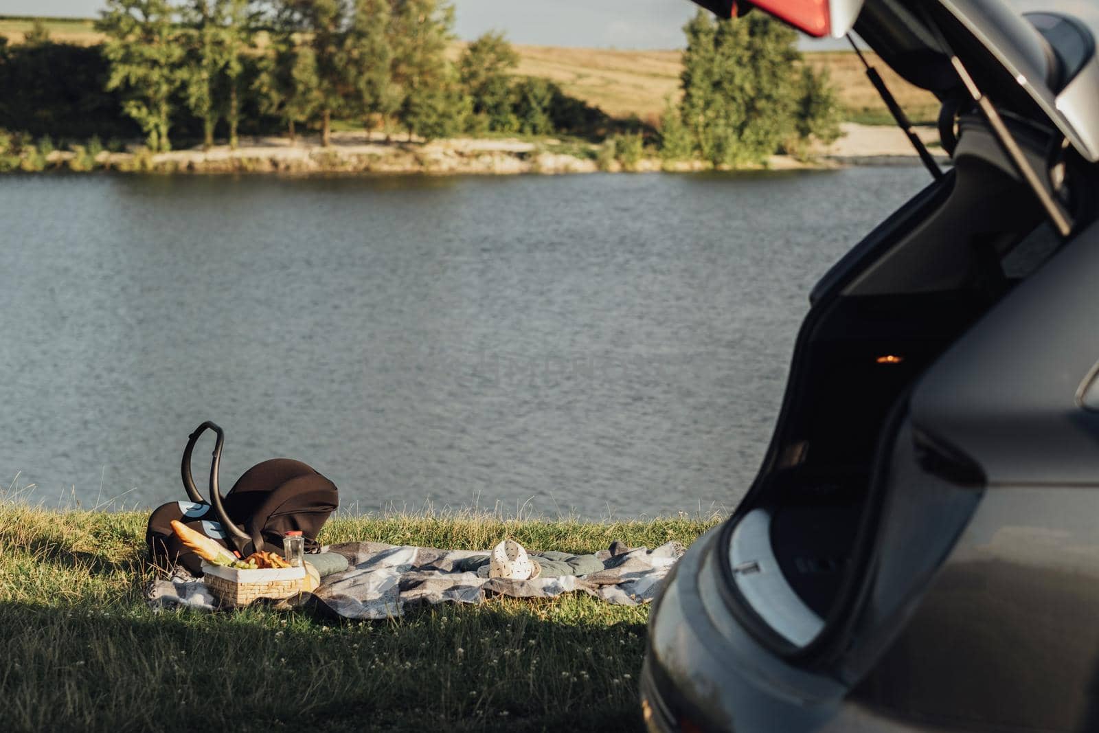 Picnic Set Outdoors by Lake at Sunset, Child Car Seat, Road Trip Concept