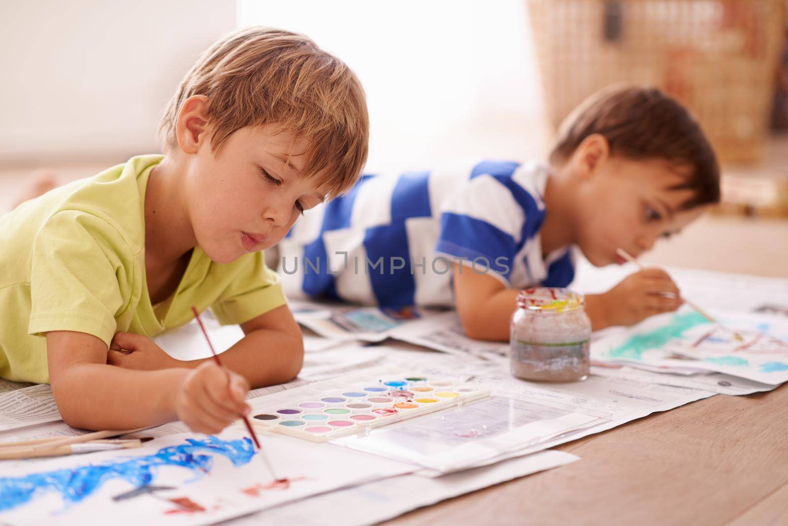 Shot of two young boys painting pictures at home.