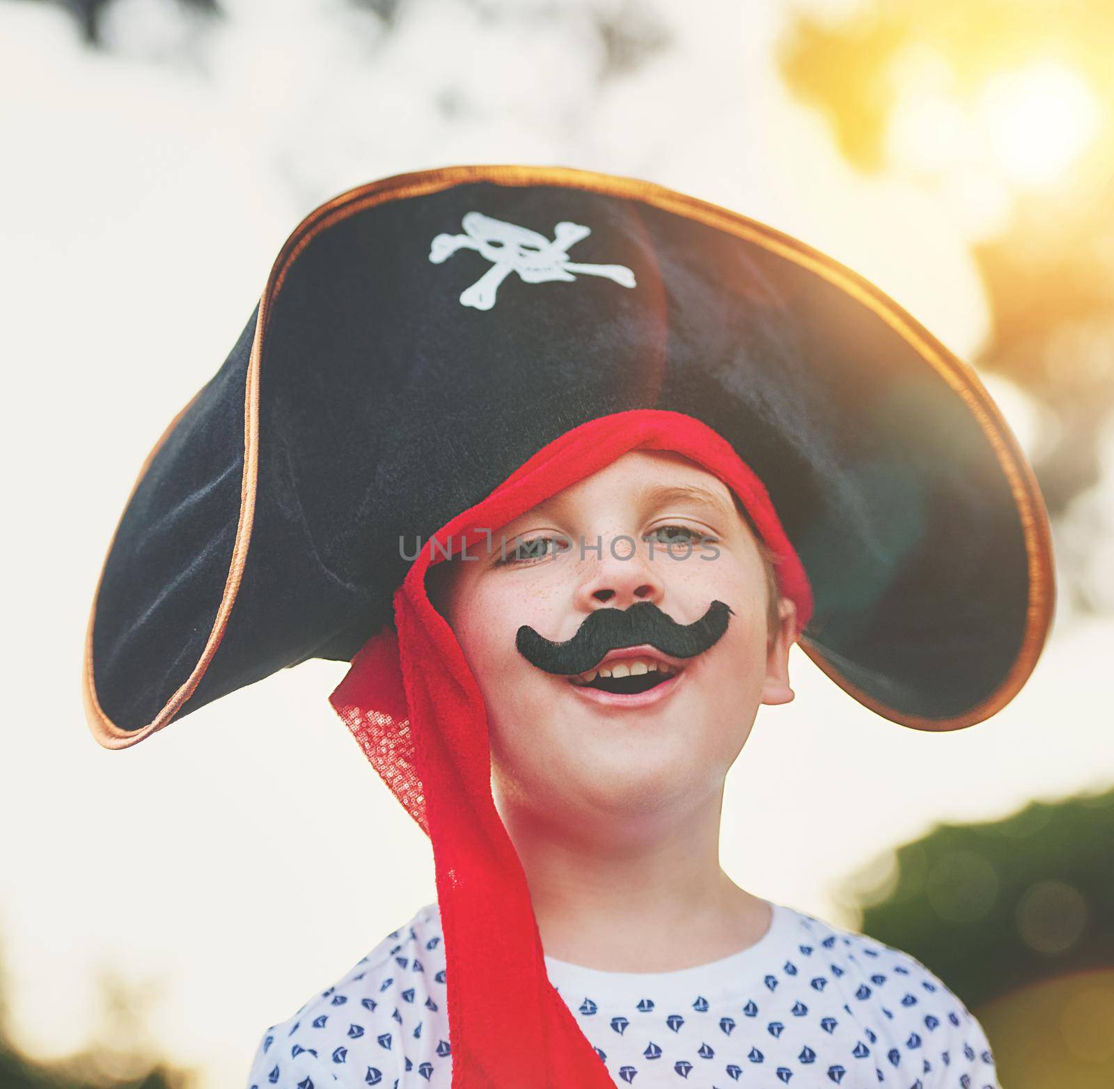 Portrait of a cute little boy posing outside while dressed up like a pirate.