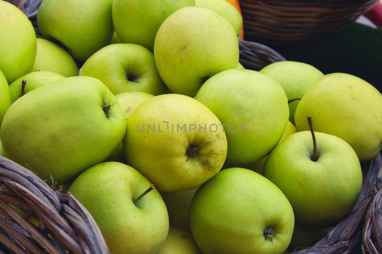 Close up of tasty green apples in a wicker basket for sale at a farmer's market