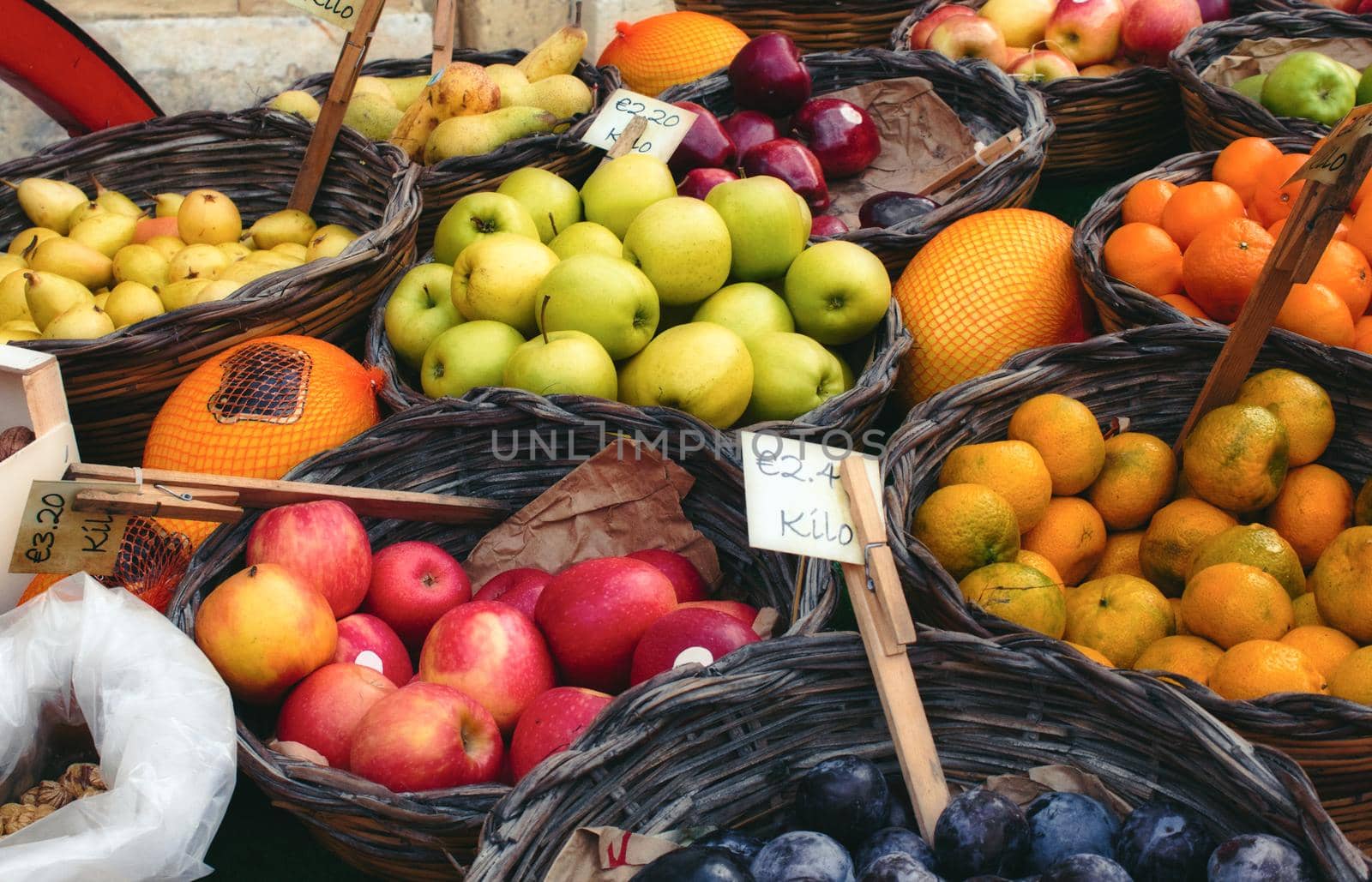 Market vendor cart with varied fruit in wicker baskets