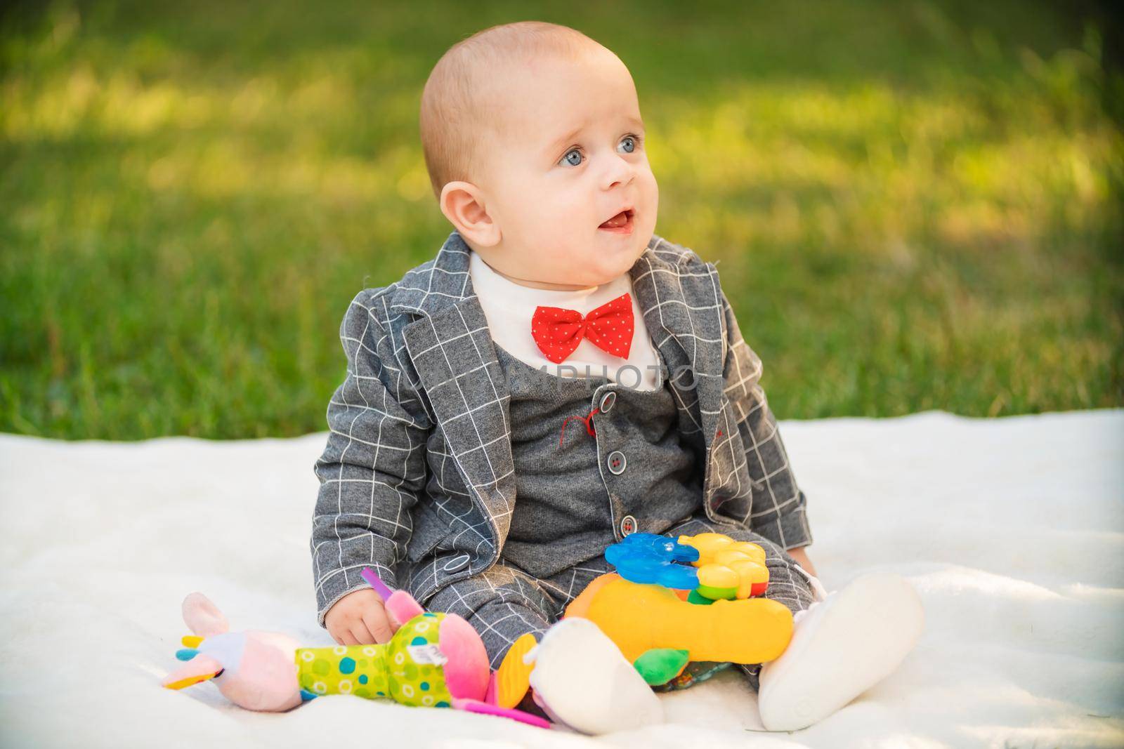 boy sitting on a white blanket with toys