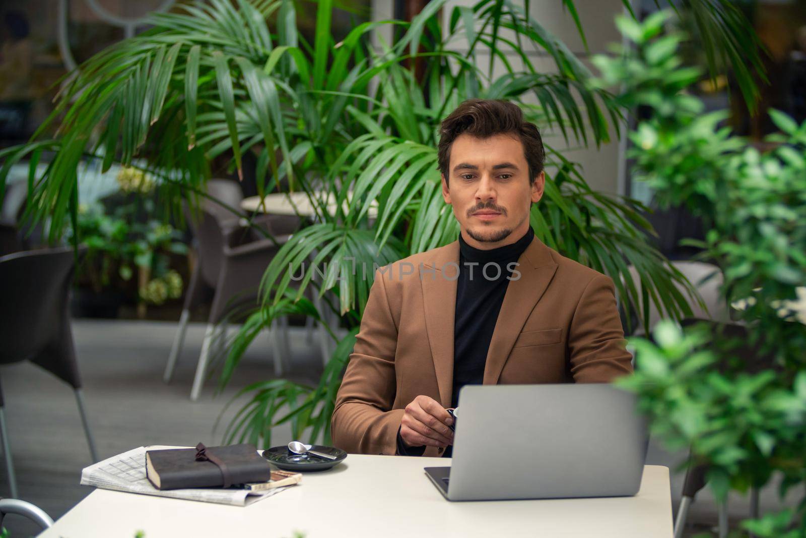 businessman sitting at a table in a cafe with a laptop