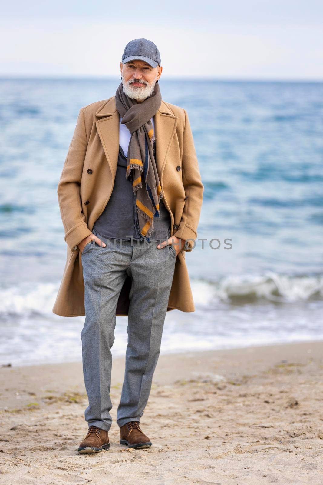 an aged man walking along the beach against the background of the sea