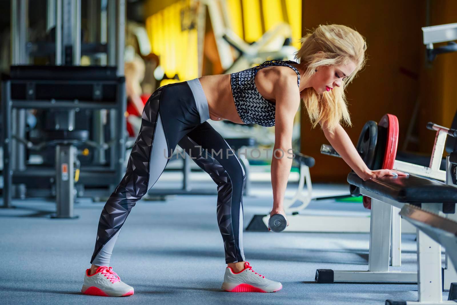 girl works out in the gym using a dumbbell