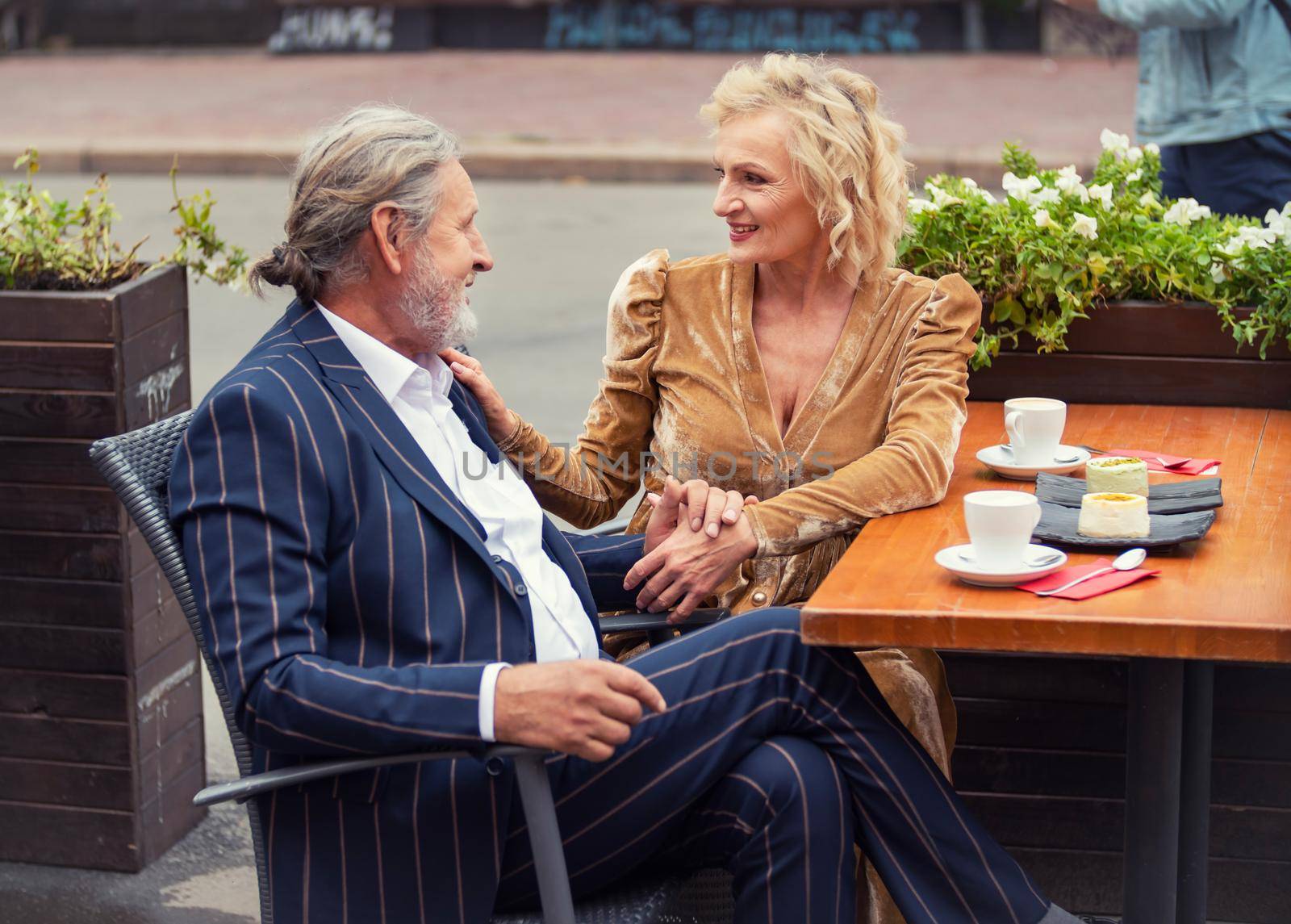 elderly couple sitting at a table on the street