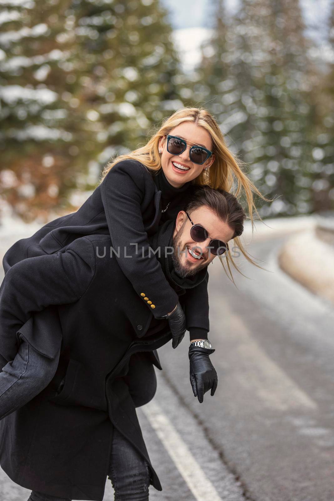 the girl climbed on the guy's back and walk along the road cheerfully