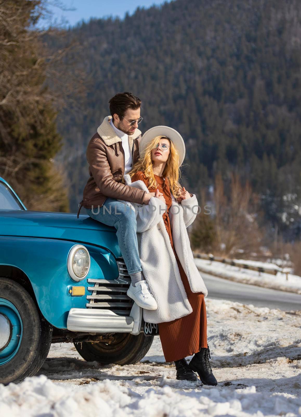 couple sitting in winter near a retro car