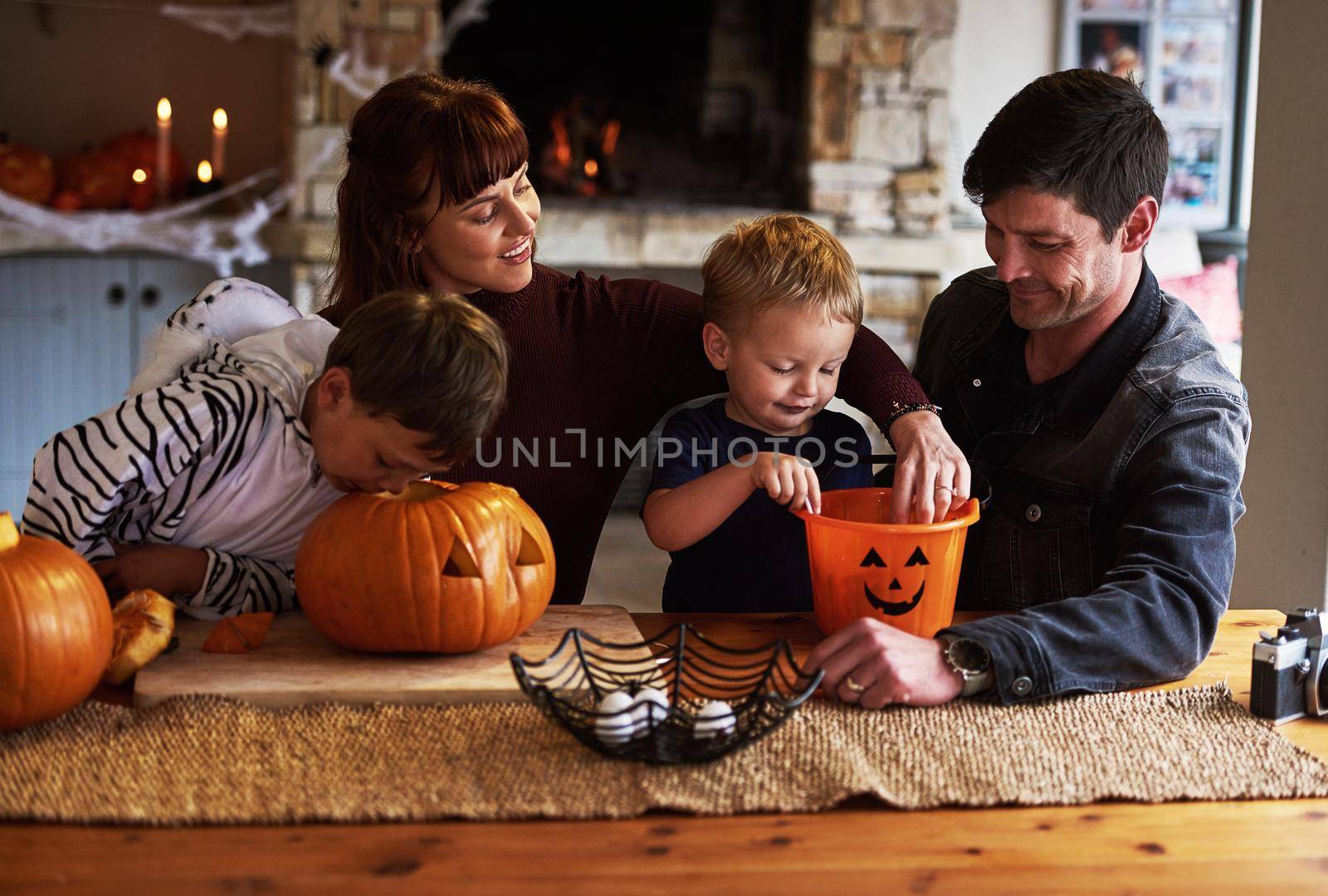 Were digging into the halloween festivities. Shot of an adorable young family carving out pumpkins and celebrating halloween together at home. by YuriArcurs