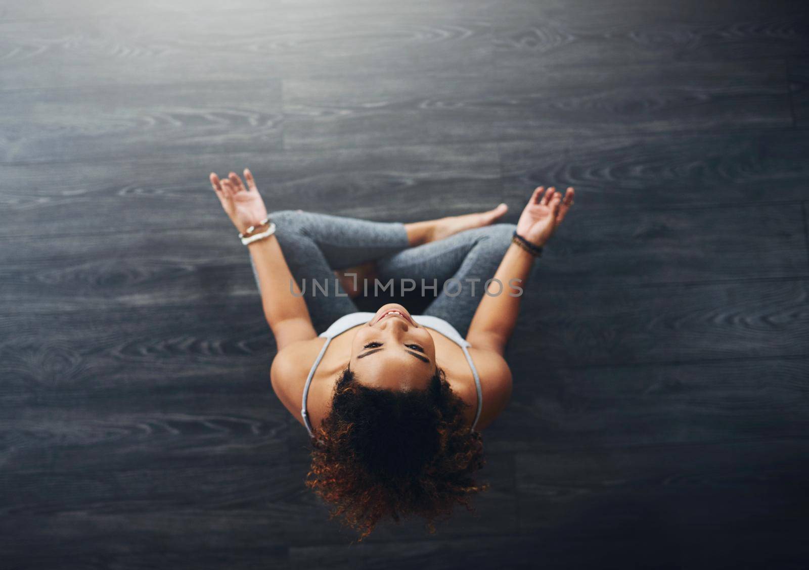 Never hesitate to meditate. High angle shot of a young woman practising yoga. by YuriArcurs