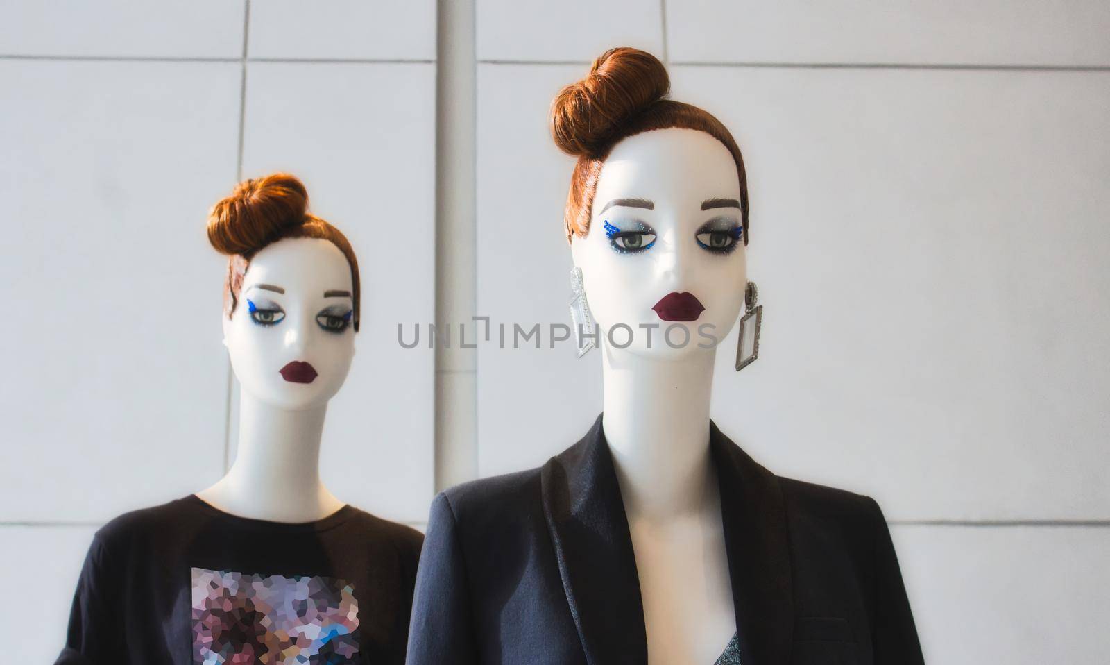 Two identical white fashion mannequins displaying modern clothes