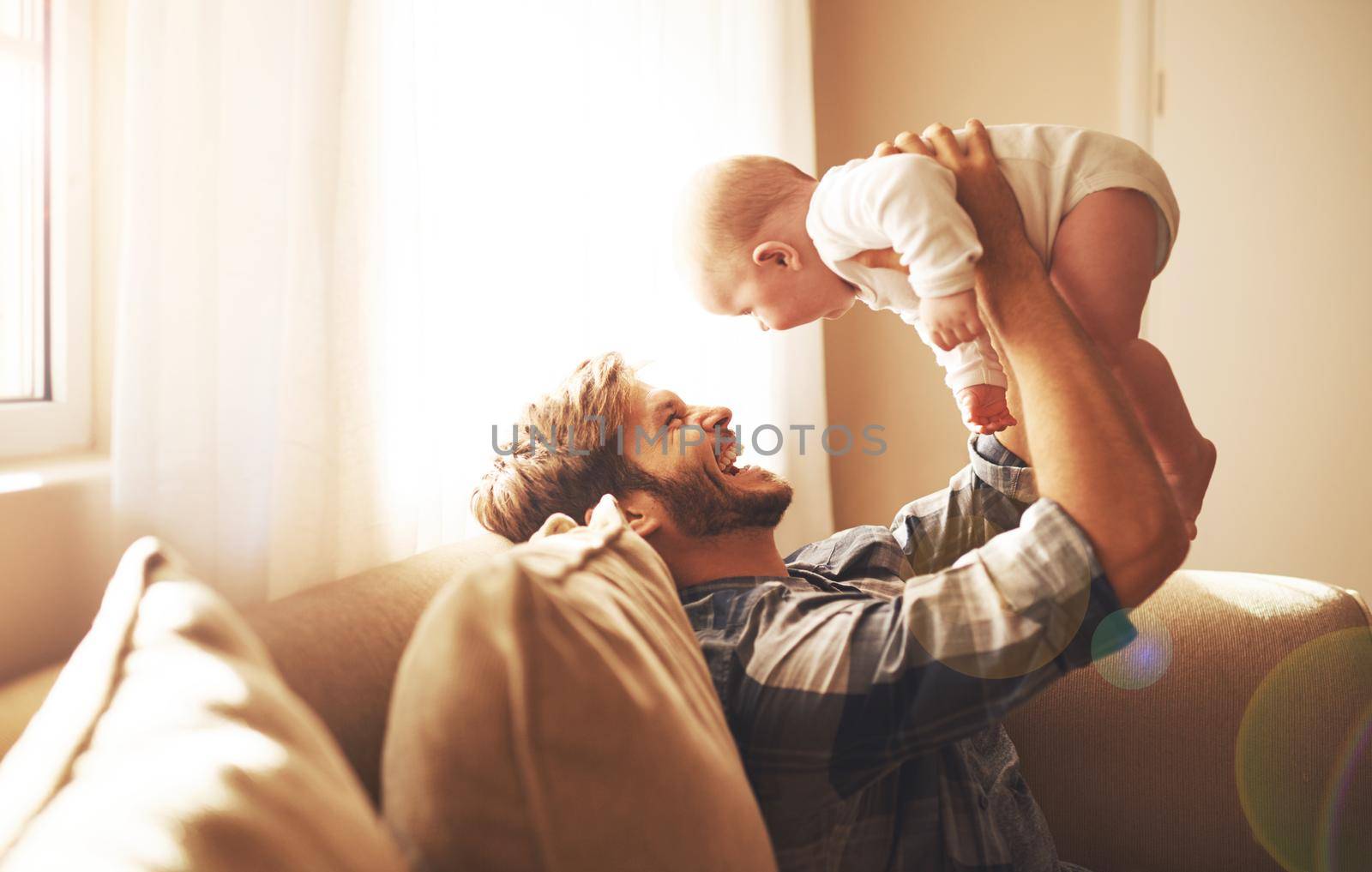 Raising his boy with so much love. Cropped shot of a young father and his baby boy in the living room. by YuriArcurs
