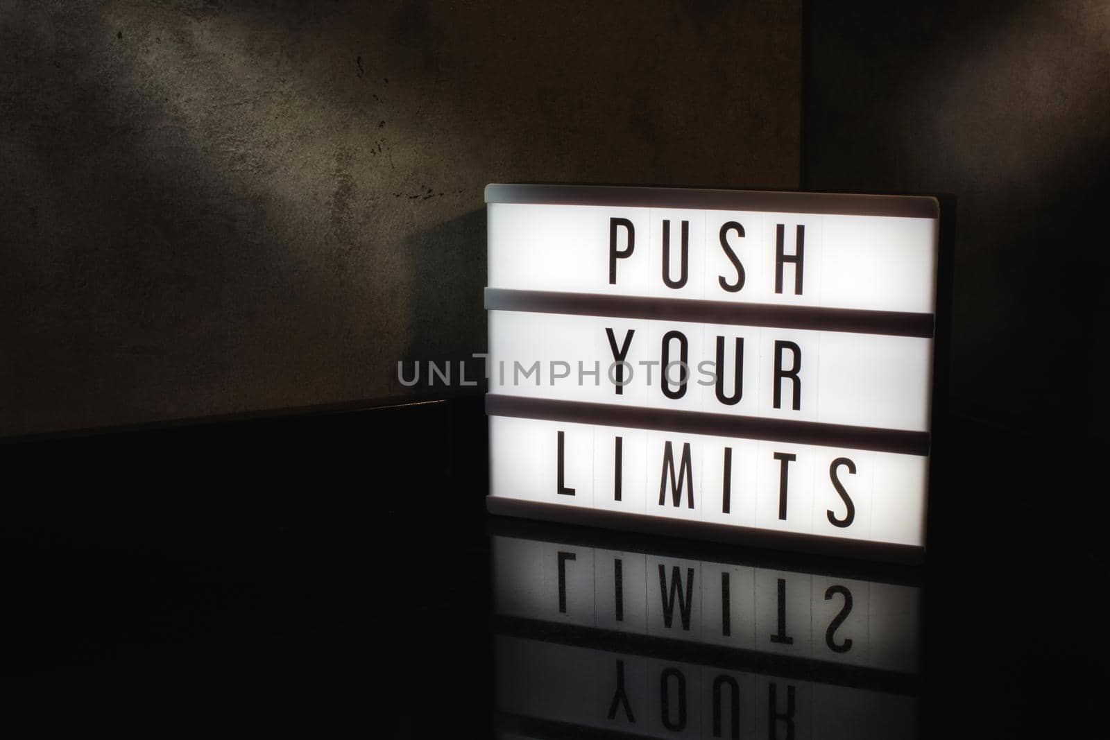 Push your limits motivational message on a light box in a cinematic moody background