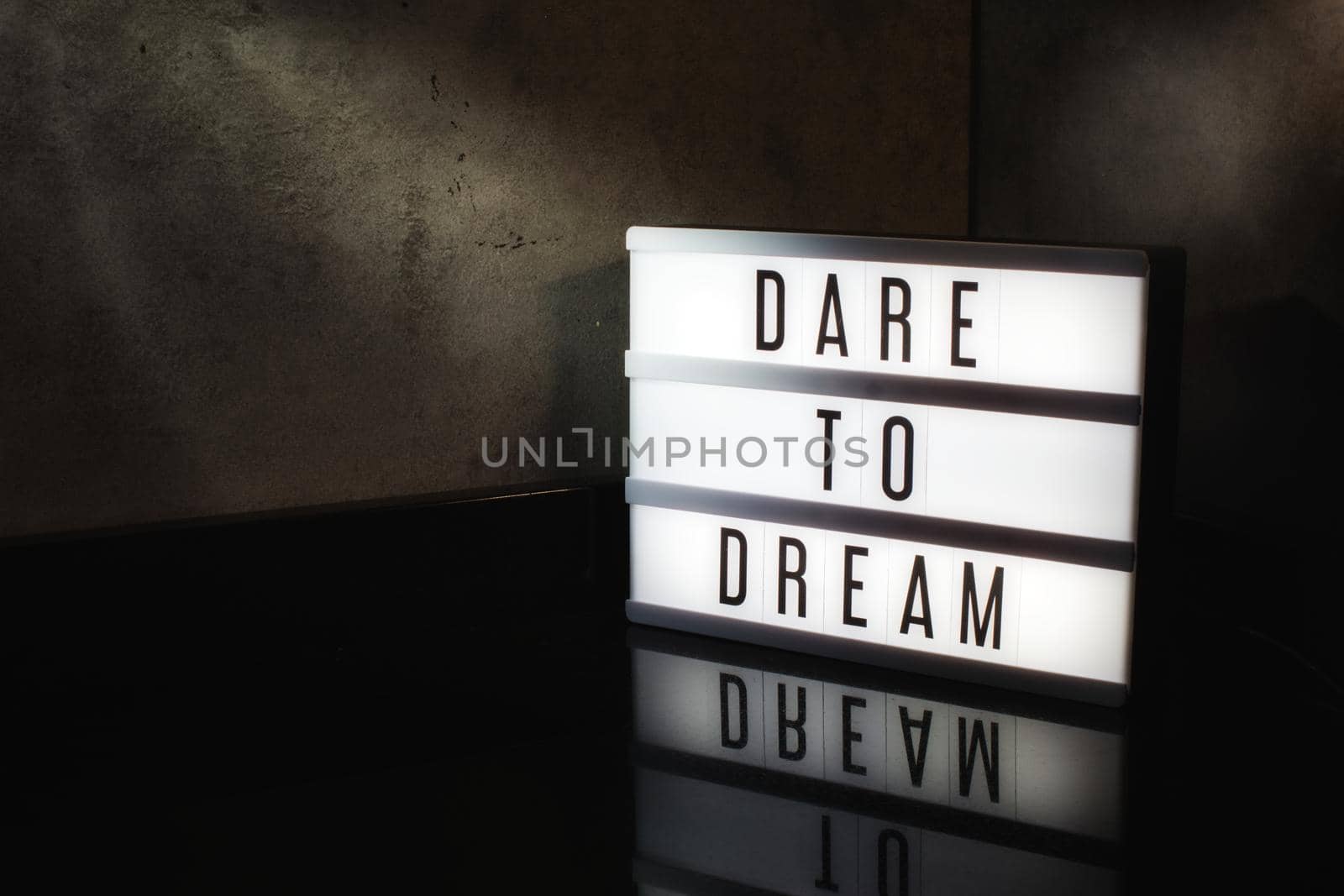 Dare to dream motivational message on a light box in a cinematic moody background