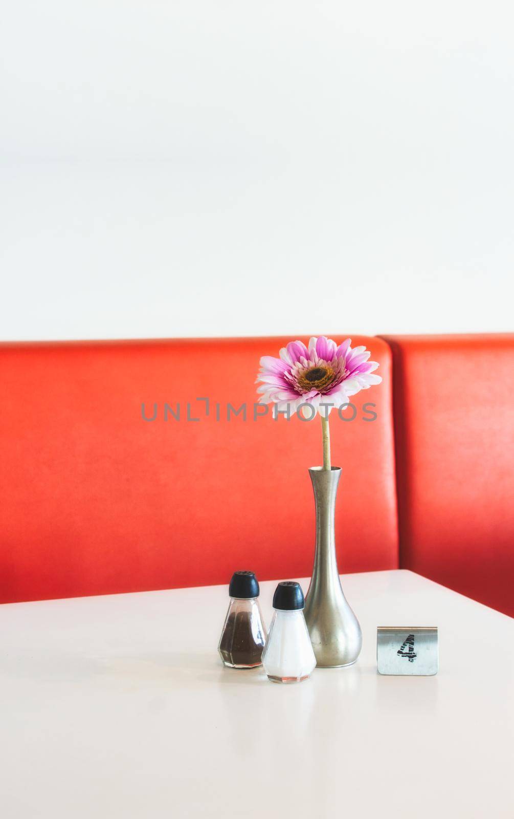 Indoor table setting in a cafe copy-space with flower in pot, salt and pepper shakers and metal number marker