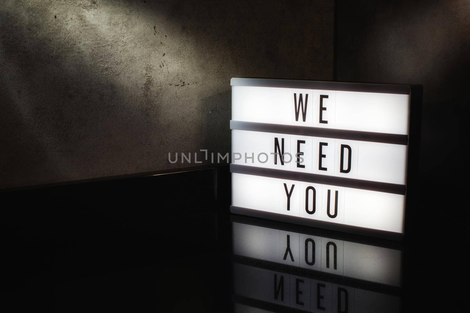 We need you recruitment message on a light box in a cinematic moody background