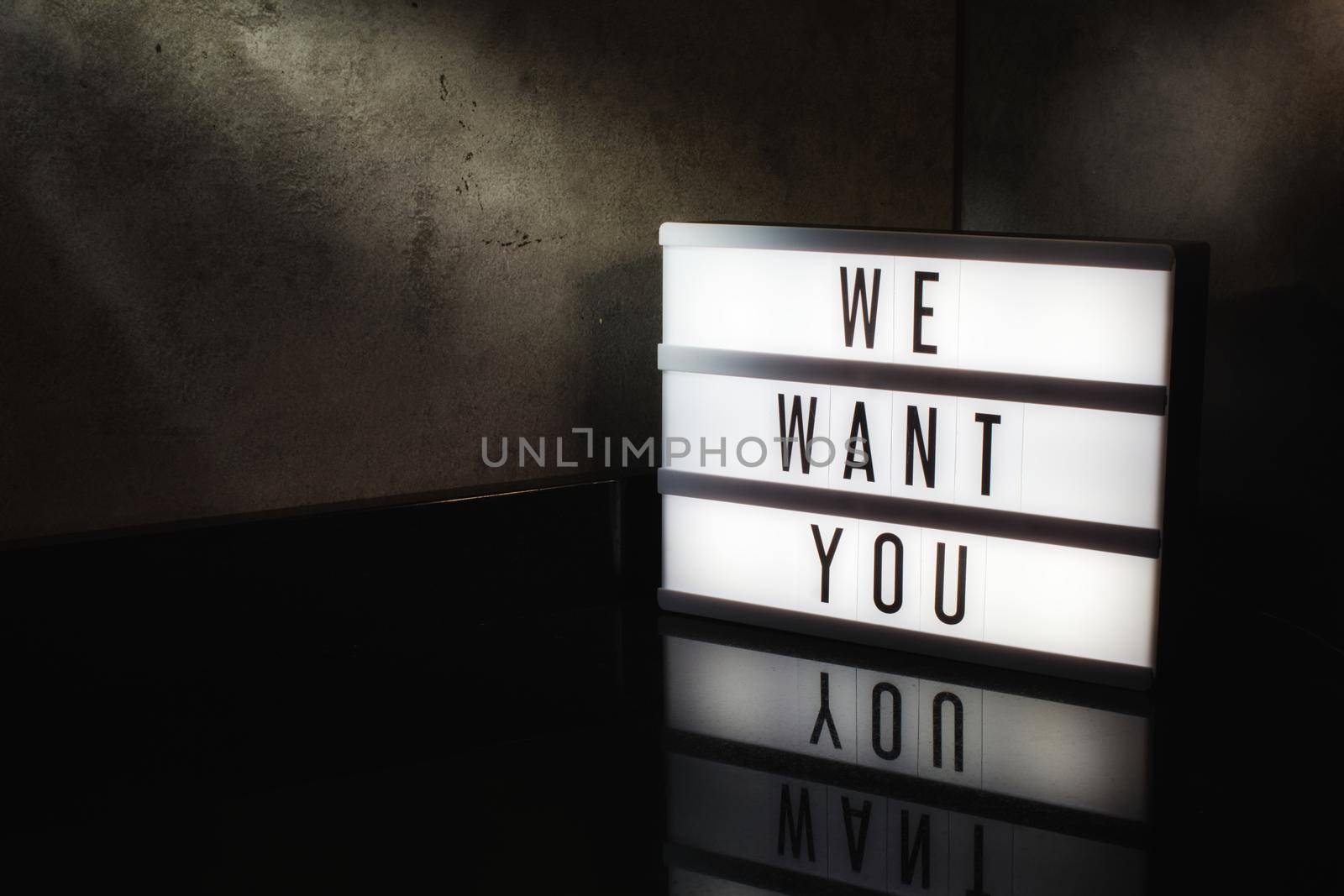 We want you recruitment message on a light box in a cinematic moody background