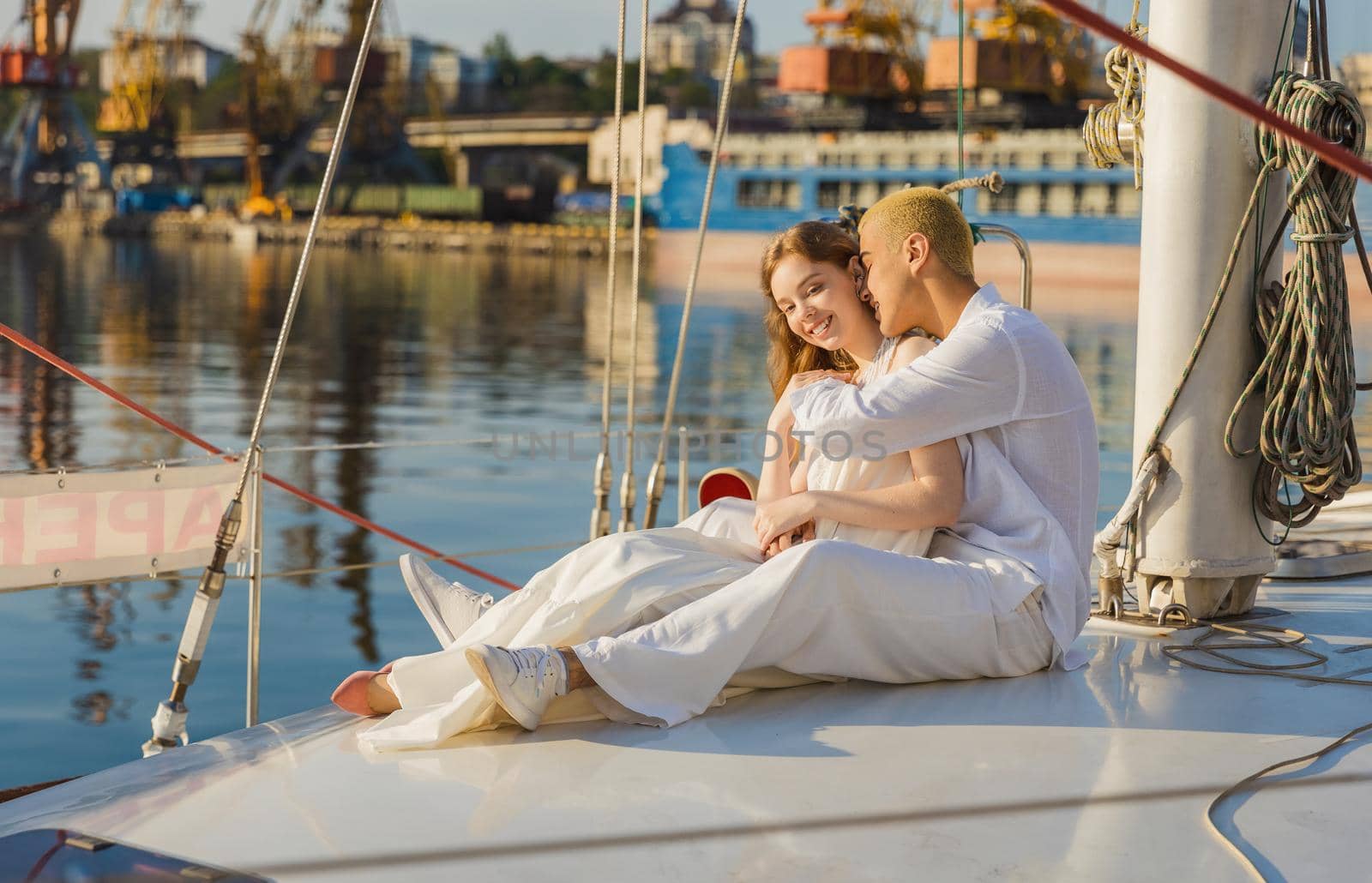 couple in white clothes sitting on board the yacht