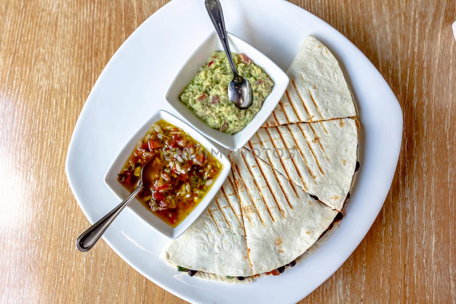 Savory crepe filled with spicy ground beef, cheese, kidney beans, lettuce and tomatoes. Topped with sour cream and served on a plate. Tex mex food.