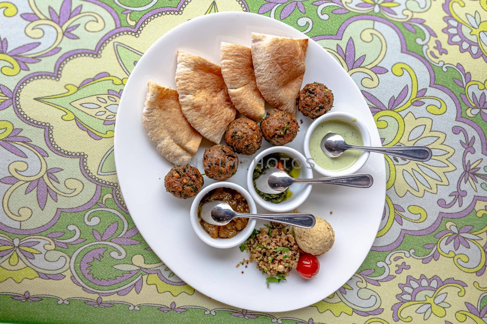Traditional middle eastern homemade dishes falafel, pita, hummus and chickpea served with vegetables and spices on woodwn table by Milanchikov