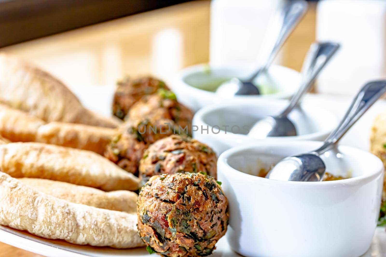 Traditional middle eastern homemade dishes falafel, pita, hummus and chickpea served with vegetables and spices on woodwn table by Milanchikov