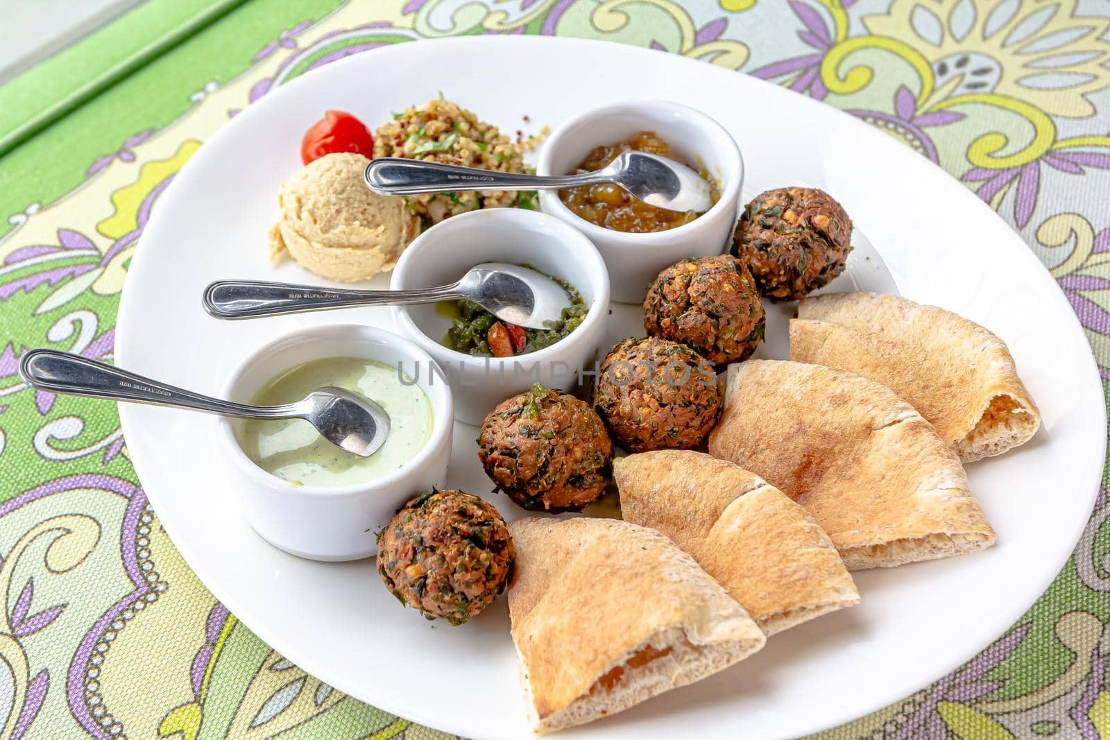 Traditional middle eastern homemade dishes falafel, pita, hummus and chickpea served with vegetables and spices on woodwn table by Milanchikov