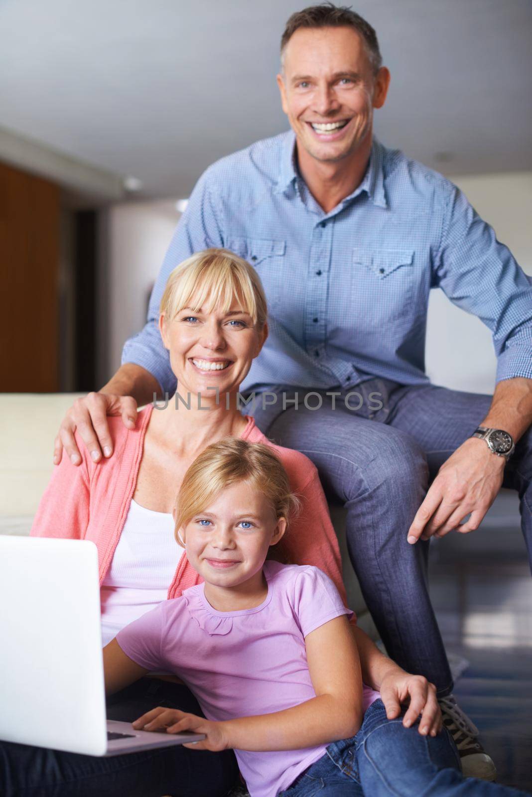 A family of three using a laptop in the lounge.