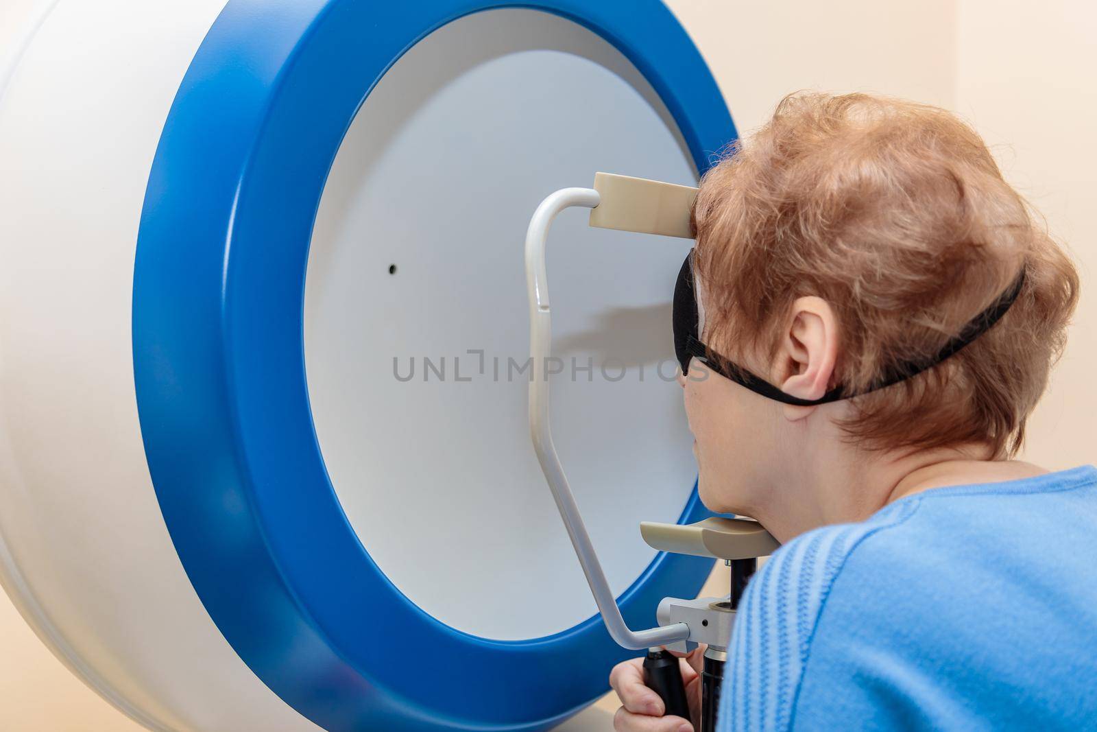 An adult girl at an ophthalmologist's appointment checks her eyesight on a special apparatus. Close-up.